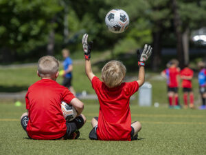 Två sittande pojkar med en fotboll i luften.